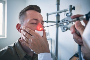 Doctor doing nose examination of young patient Medizinische Lasertechnologie